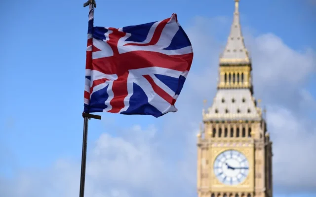 Drapel britanic pe un catarg, cu turnul Elizabeth din Londra în fundal