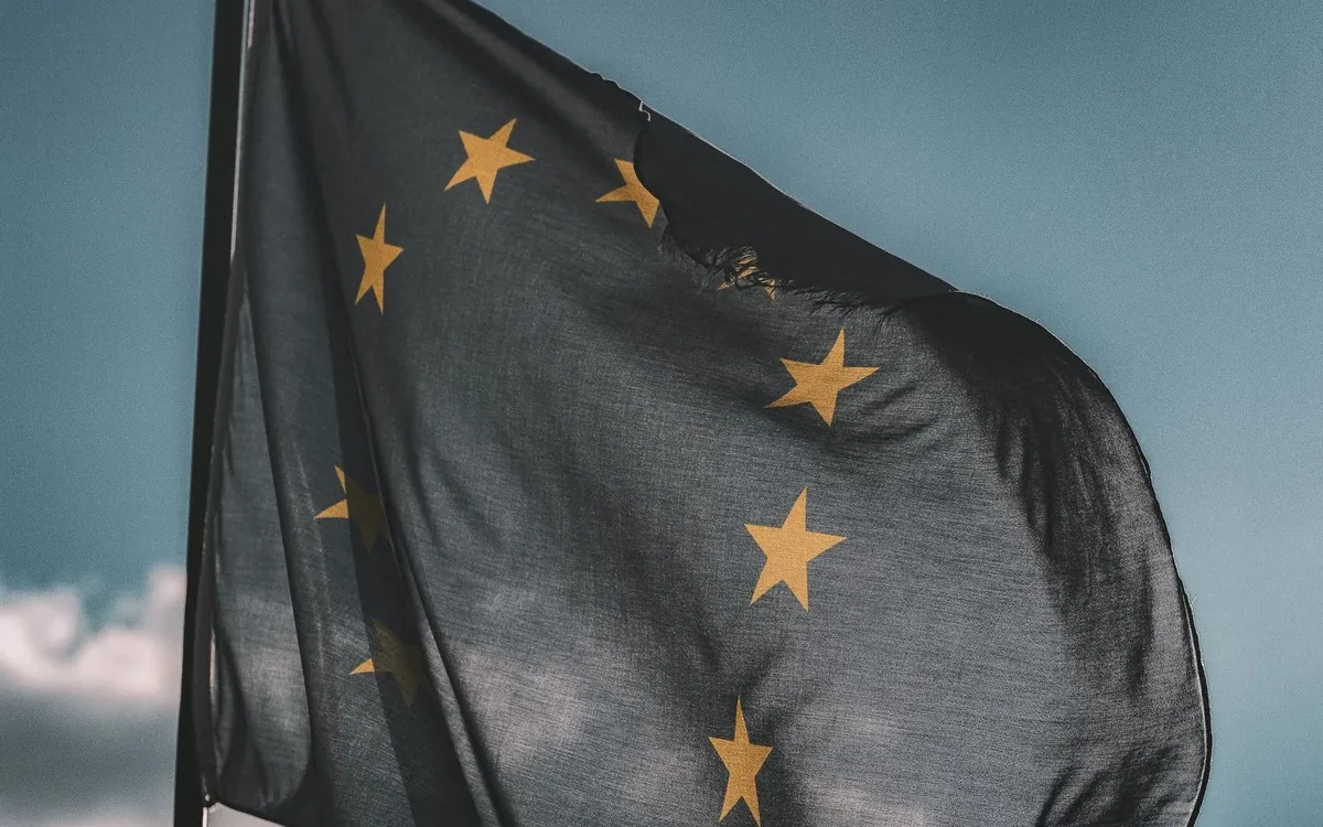 Drapel albastru al Uniunii Europene cu stele galbene, pe un catarg, pe fundal de cer