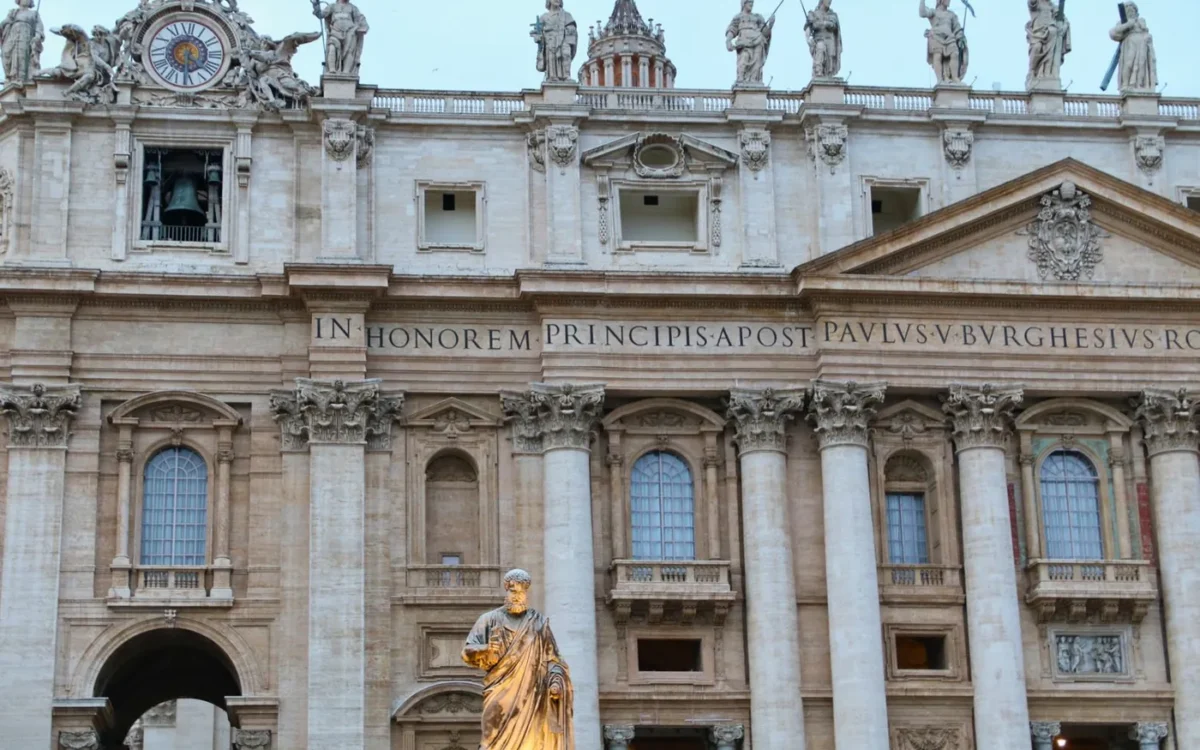 Fațada Bazilicii Sfântul Petru din Vatican, cu coloane și statui sub cer albastru