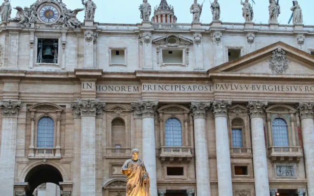 Fațada Bazilicii Sfântul Petru din Vatican, cu coloane și statui sub cer albastru