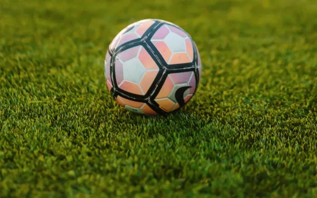 Minge de fotbal cu panouri albe, roz și negre pe gazon verde