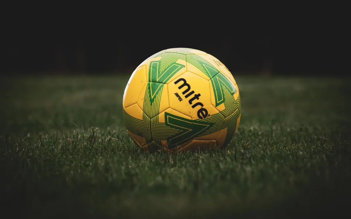 Minge galbenă de fotbal cu model verde pe gazon