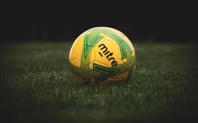 Minge galbenă de fotbal cu model verde pe gazon