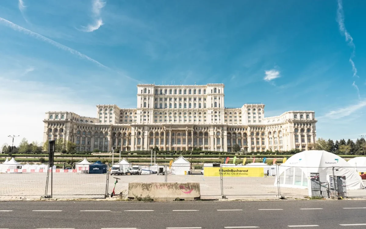 Fațada Palatului Parlamentului din București, cu spațiu verde și corturi în prim-plan