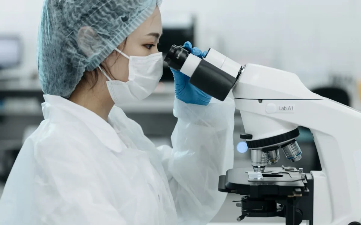 Persoană cu echipament de protecție la microscop