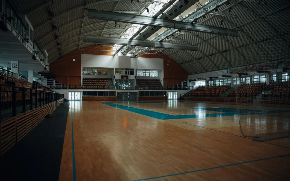 Sală de sport goală, cu parchet și porți de handbal