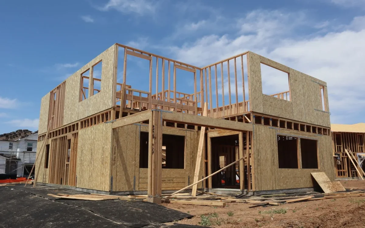 Casă cu două niveluri în construcție, cu structură din lemn și panouri, sub cer albastru