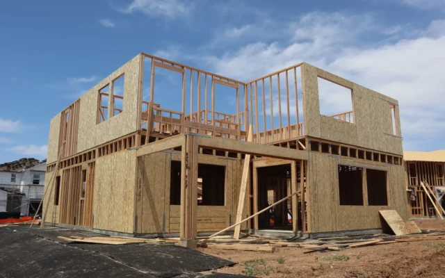 Casă cu două niveluri în construcție, cu structură din lemn și panouri, sub cer albastru